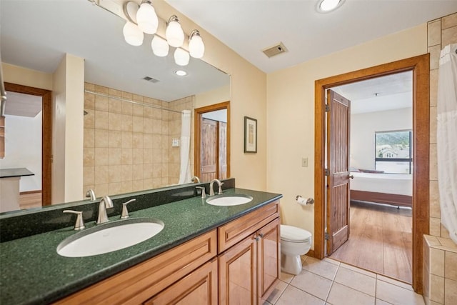 ensuite bathroom with visible vents, a sink, and tile patterned flooring