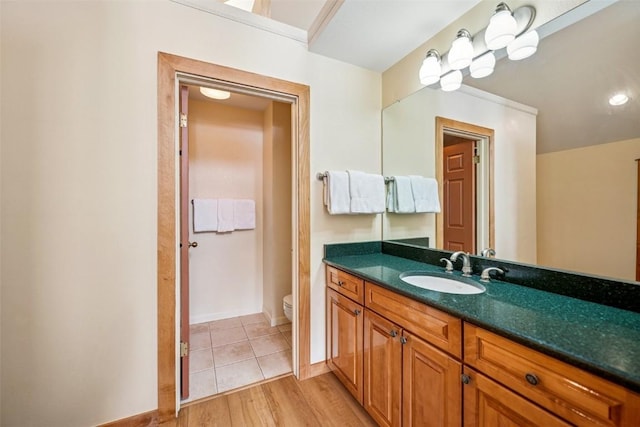 bathroom featuring vanity, baseboards, wood finished floors, and toilet