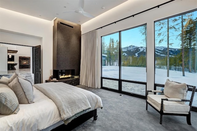 carpeted bedroom with a towering ceiling, a mountain view, a multi sided fireplace, and access to exterior