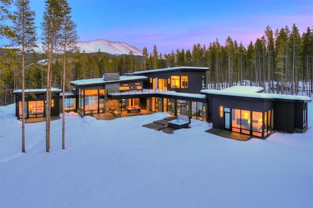 snow covered property featuring a view of trees and a mountain view