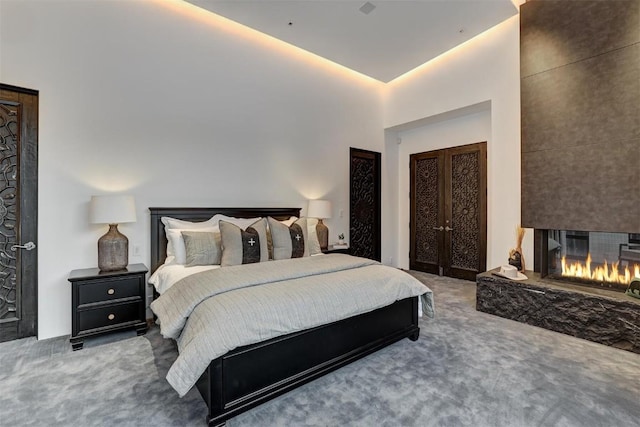 carpeted bedroom featuring french doors and a large fireplace
