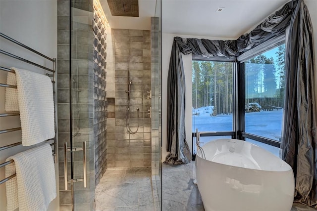 bathroom featuring marble finish floor, a freestanding tub, and a stall shower