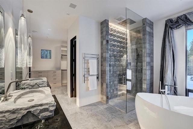 bathroom featuring a soaking tub, a stall shower, marble finish floor, vanity, and a walk in closet