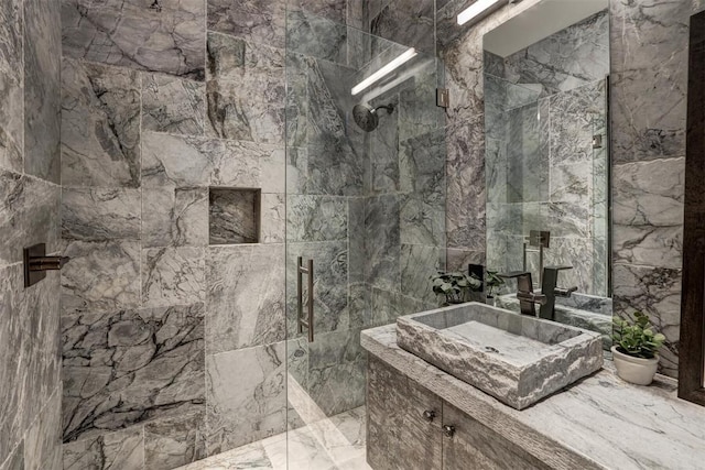 full bath featuring tile walls, a marble finish shower, marble finish floor, and vanity