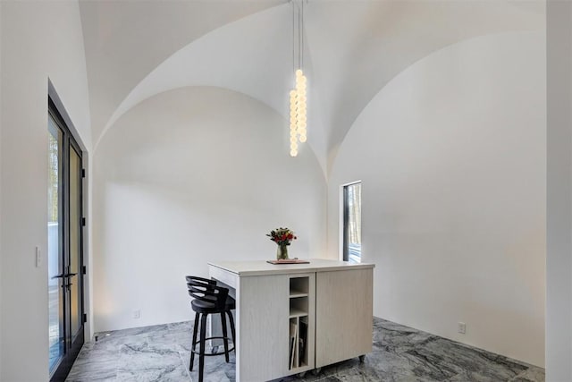 dining space featuring lofted ceiling, plenty of natural light, marble finish floor, and arched walkways