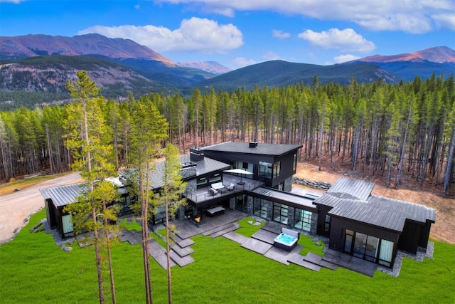 back of house featuring a lawn, a wooded view, and a mountain view