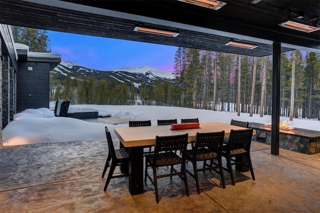 view of patio featuring a forest view, outdoor dining area, and a mountain view
