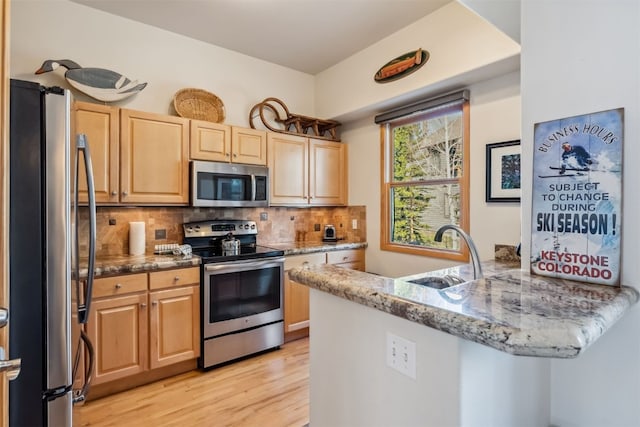 502 Northstar Dr Unit 1947, Keystone, CO 80435 - kitchen featuring appliances with stainless steel finishes, a sink, light wood finished floors, a peninsula, and light stone countertops