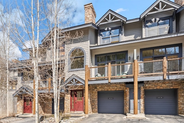 502 Northstar Dr Unit 1947, Keystone, CO 80435 - view of front facade with a balcony, a chimney, an attached garage, asphalt driveway, and stone siding