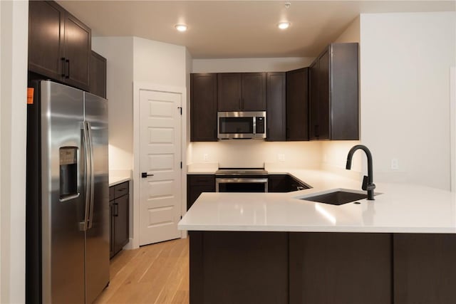 35 Argentine Ct Unit 307, Keystone, CO 80435 - kitchen with appliances with stainless steel finishes, a peninsula, dark brown cabinetry, light wood-type flooring, and light countertops