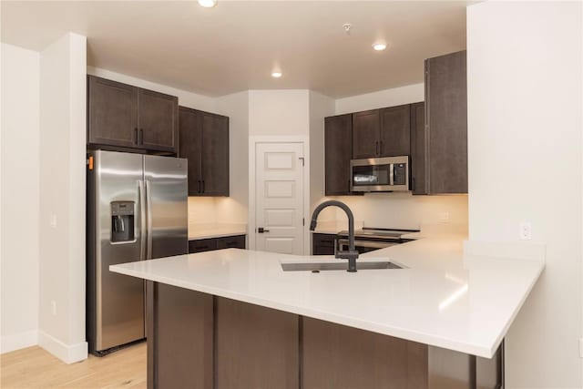 35 Argentine Ct Unit 307, Keystone, CO 80435 - kitchen with stainless steel appliances, a peninsula, dark brown cabinets, light countertops, and light wood-style flooring