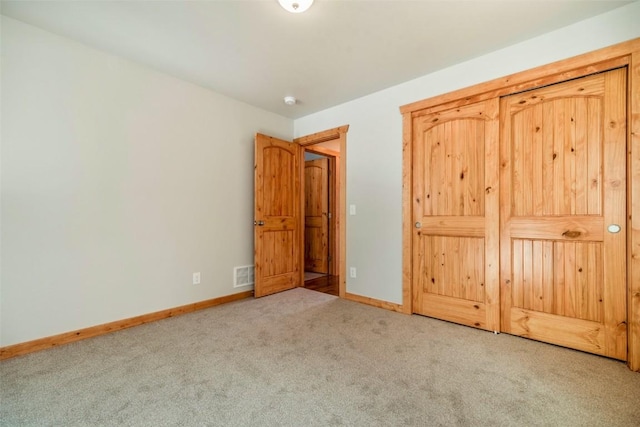 unfurnished bedroom featuring baseboards, carpet flooring, and visible vents