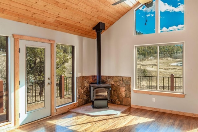 interior space featuring wood finished floors, a wood stove, visible vents, wood ceiling, and ceiling fan