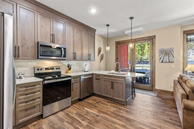 102 Lake Ridge Cir Unit 1887, Keystone, CO 80435 - kitchen with stainless steel appliances, a sink, a peninsula, dark wood-style flooring, and backsplash