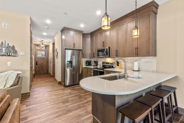 102 Lake Ridge Cir Unit 1887, Keystone, CO 80435 - kitchen featuring appliances with stainless steel finishes, a peninsula, a sink, light wood-style floors, and light countertops