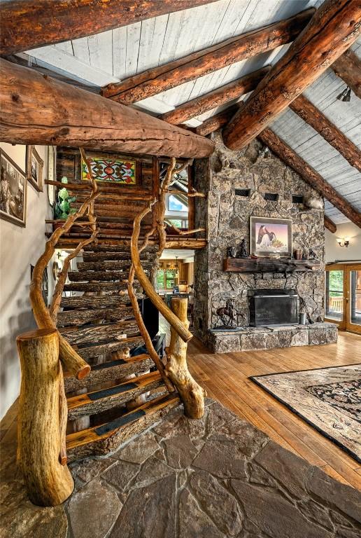 2350 Glacier Rdg, Steamboat Springs, CO 80487 - unfurnished living room featuring stairway, a stone fireplace, vaulted ceiling with beams, wood ceiling, and wood-type flooring