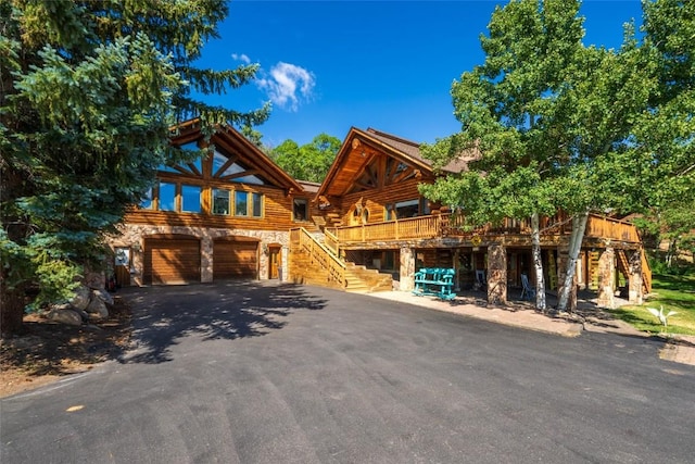 2350 Glacier Rdg, Steamboat Springs, CO 80487 - log cabin with driveway, stone siding, log siding, an attached garage, and stairs