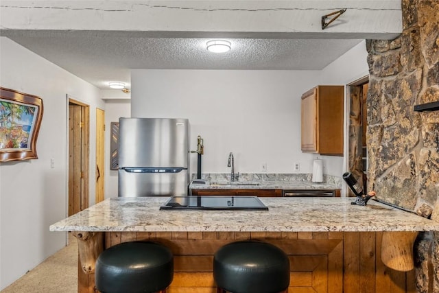 2350 Glacier Rdg, Steamboat Springs, CO 80487 - kitchen featuring a sink, light colored carpet, freestanding refrigerator, black electric cooktop, and brown cabinetry