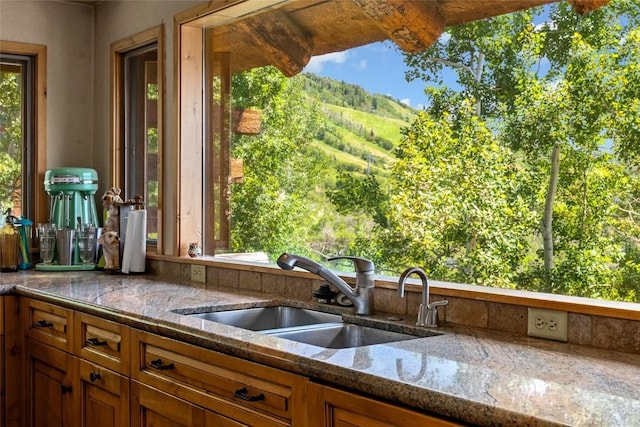 2350 Glacier Rdg, Steamboat Springs, CO 80487 - kitchen with brown cabinets, stone countertops, a sink, and a mountain view