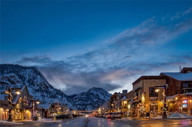 view of street featuring a mountain view, sidewalks, curbs, and street lighting