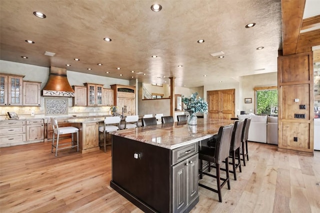 17 James Ct, Dillon, CO 80435 - kitchen with custom range hood, a kitchen bar, a spacious island, light wood-style flooring, and recessed lighting