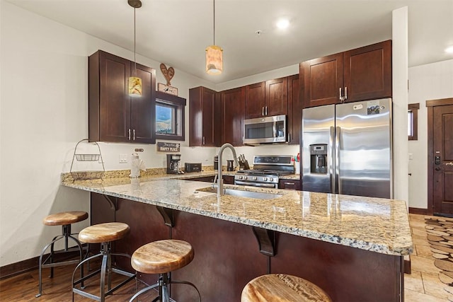 830 Blue River Pkwy Unit 203, Silverthorne, CO 80498 - kitchen with appliances with stainless steel finishes, a peninsula, light stone counters, a sink, and baseboards