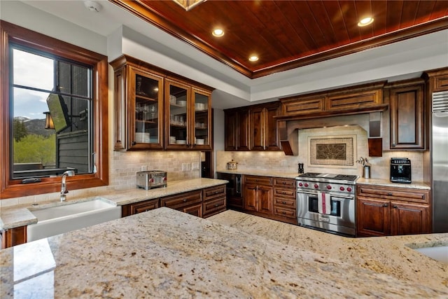 1115 Steamboat Blvd, Steamboat Springs, CO 80487 - kitchen with premium appliances, a sink, light stone countertops, backsplash, and glass insert cabinets