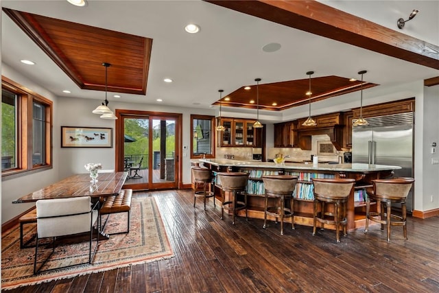 1115 Steamboat Blvd, Steamboat Springs, CO 80487 - kitchen featuring a tray ceiling, baseboards, dark wood-style floors, glass insert cabinets, and a breakfast bar area