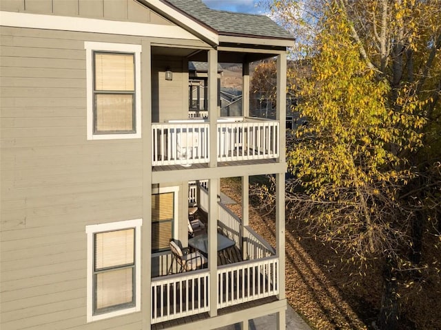 exterior space with board and batten siding, a balcony, and roof with shingles