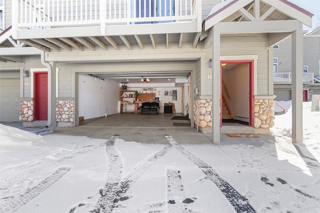 snow covered garage with a baseboard heating unit and driveway