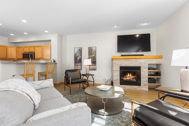 living area with recessed lighting, light wood-type flooring, baseboards, and a fireplace