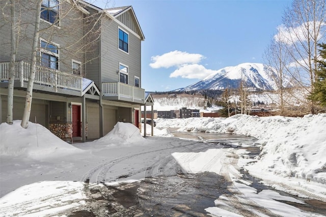 snow covered property featuring a mountain view, an attached garage, and board and batten siding