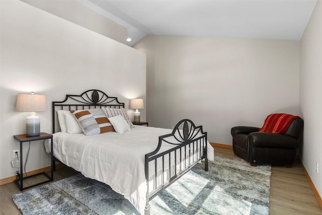 bedroom featuring vaulted ceiling, baseboards, and wood finished floors