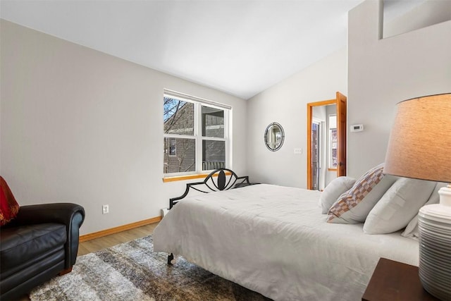 bedroom featuring baseboards, lofted ceiling, and wood finished floors