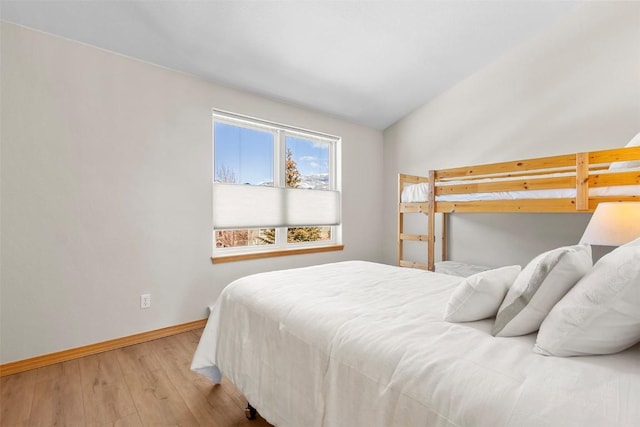 bedroom featuring lofted ceiling, baseboards, and wood finished floors