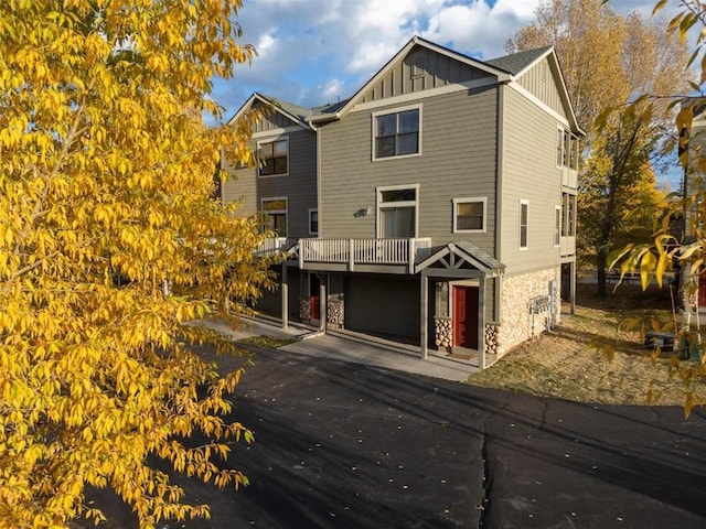 view of front facade with stone siding, board and batten siding, and driveway