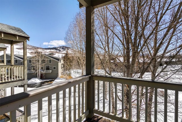 snow covered back of property featuring a mountain view