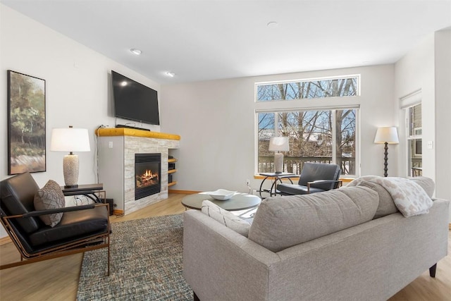 living room with a glass covered fireplace, baseboards, and wood finished floors