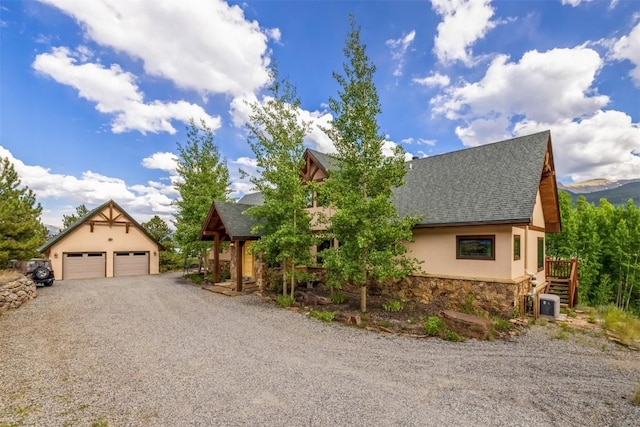 view of front of property with cooling unit, a garage, and an outbuilding