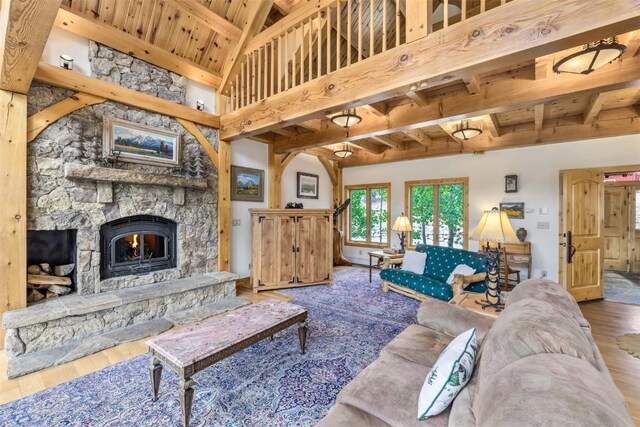 living room with hardwood / wood-style floors, high vaulted ceiling, and a stone fireplace