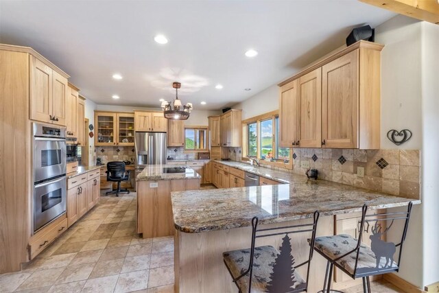 kitchen featuring decorative backsplash, appliances with stainless steel finishes, decorative light fixtures, a kitchen island, and a breakfast bar area