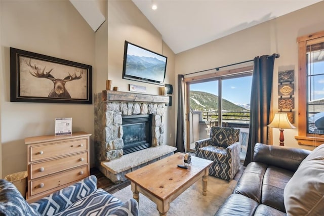 living area with plenty of natural light, high vaulted ceiling, and a stone fireplace
