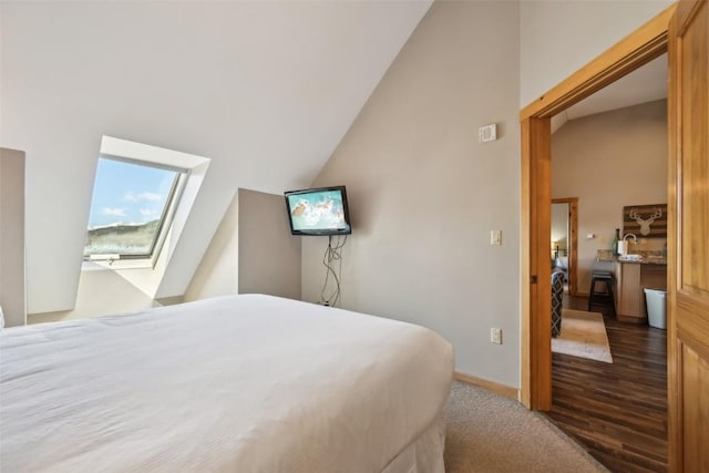 bedroom featuring baseboards, wood finished floors, and lofted ceiling with skylight