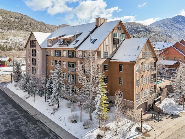 snow covered building featuring a mountain view and a garage