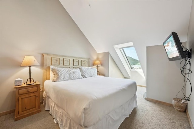 bedroom with vaulted ceiling with skylight, light carpet, and baseboards