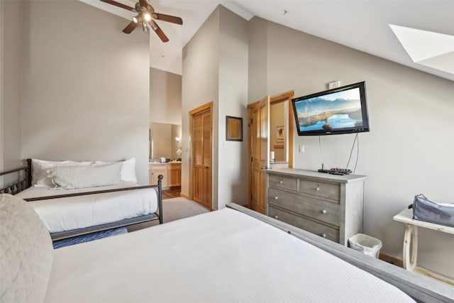 bedroom featuring ceiling fan, a closet, high vaulted ceiling, ensuite bath, and a skylight