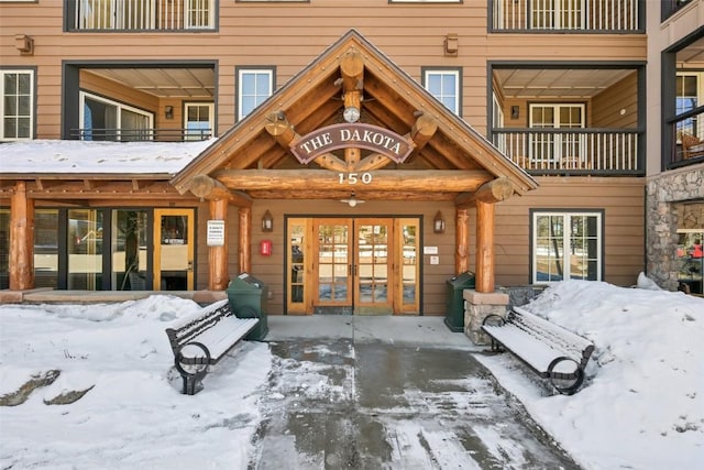 snow covered property entrance featuring french doors