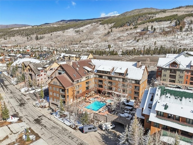 snowy aerial view with a mountain view and a residential view