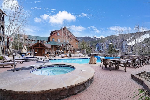 pool with a mountain view, fence, a patio area, and a hot tub
