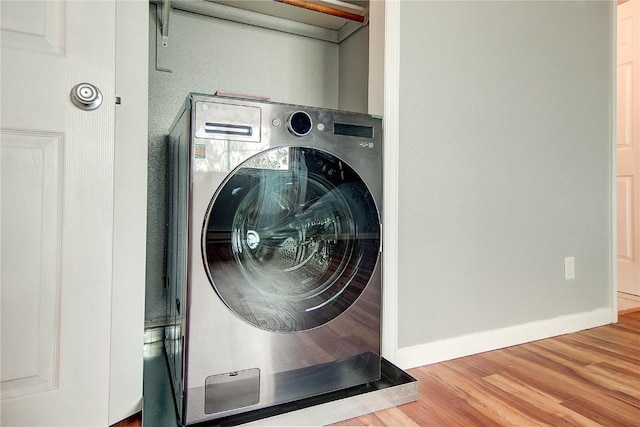 laundry area with baseboards, wood finished floors, laundry area, and washer / clothes dryer